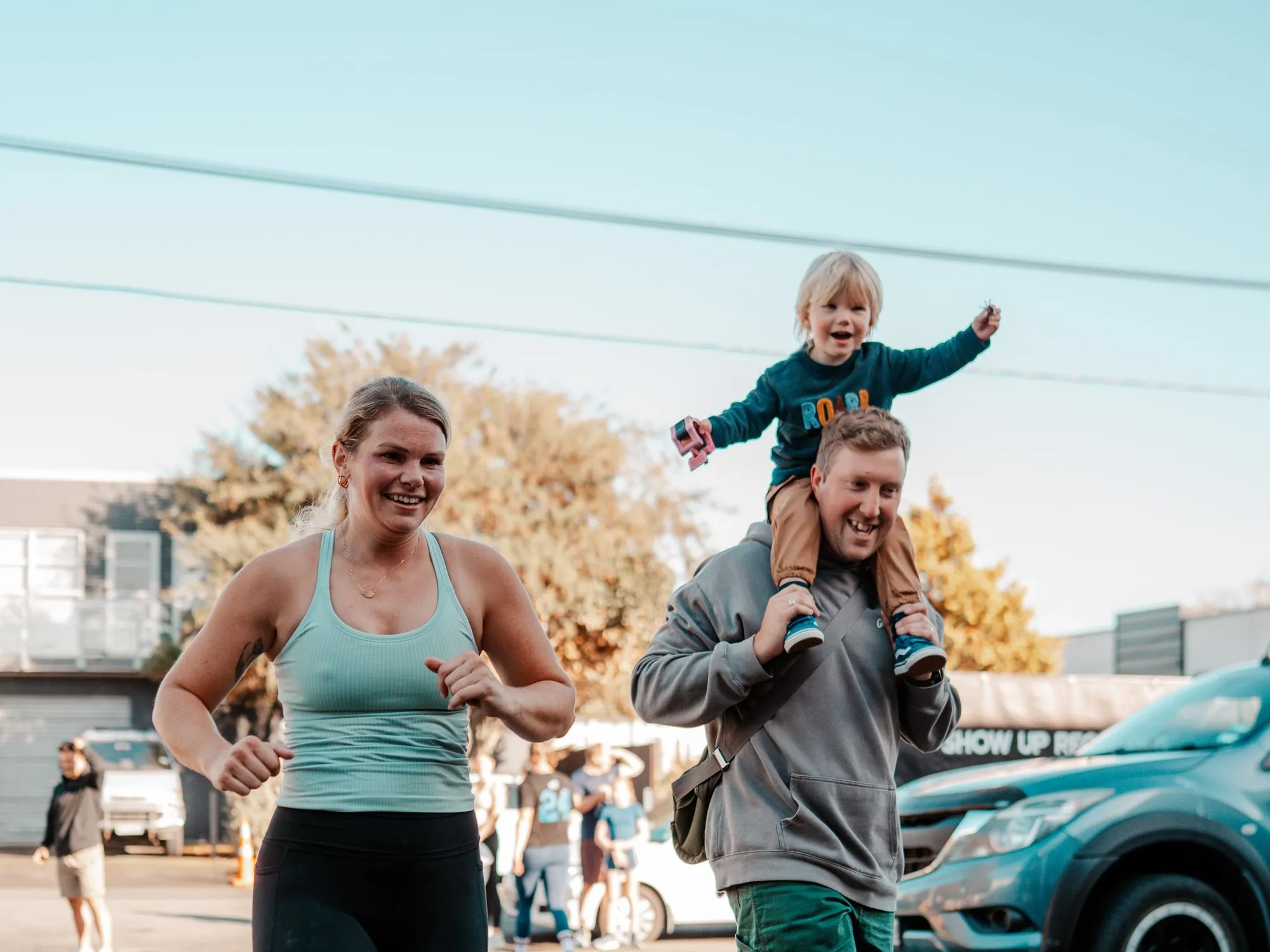 A couple jogging outside the gym, their little one riding on dad’s shoulders.