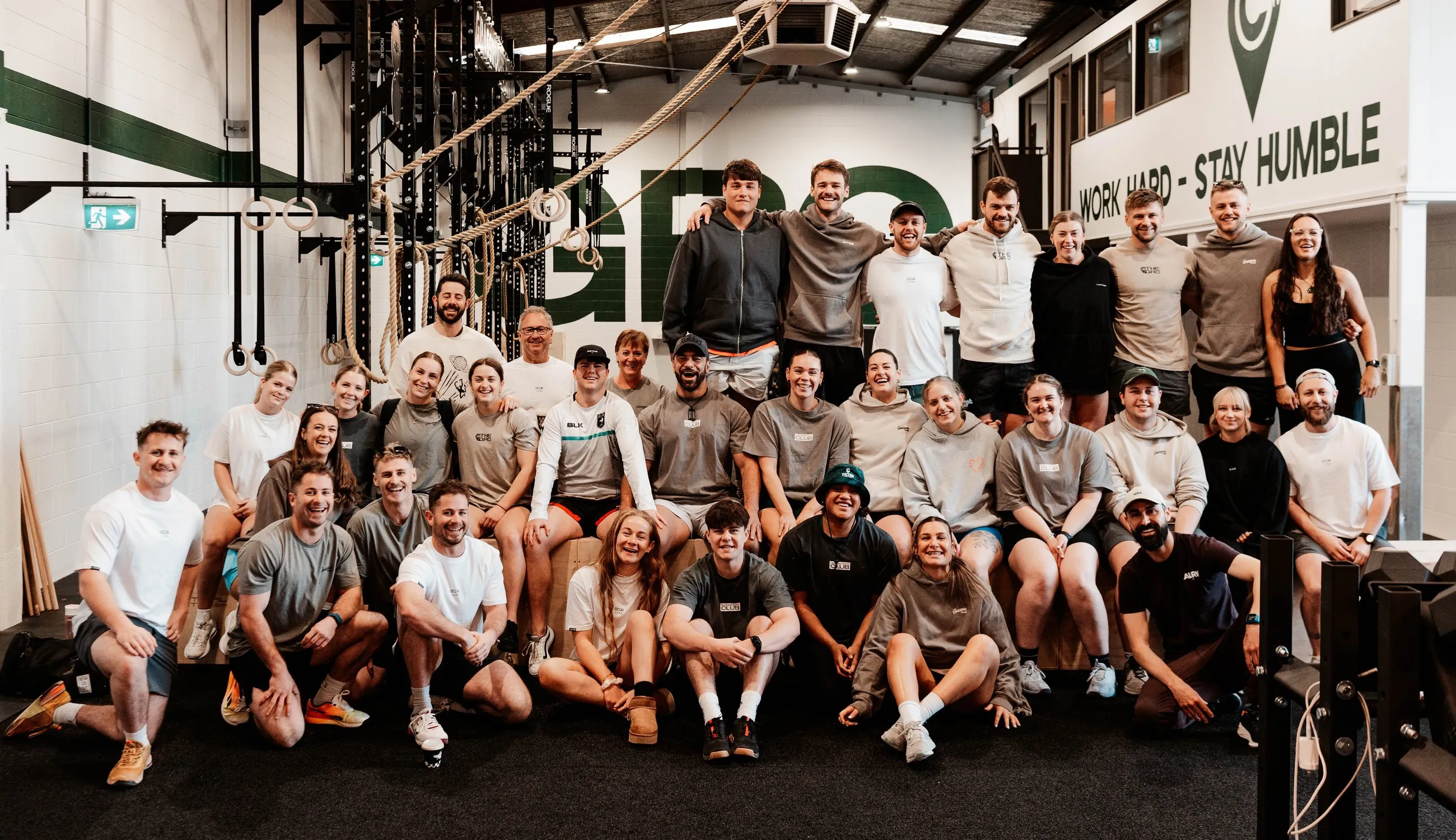 The whole club together for a group photo under the Work Hard, Stay Humble wall.