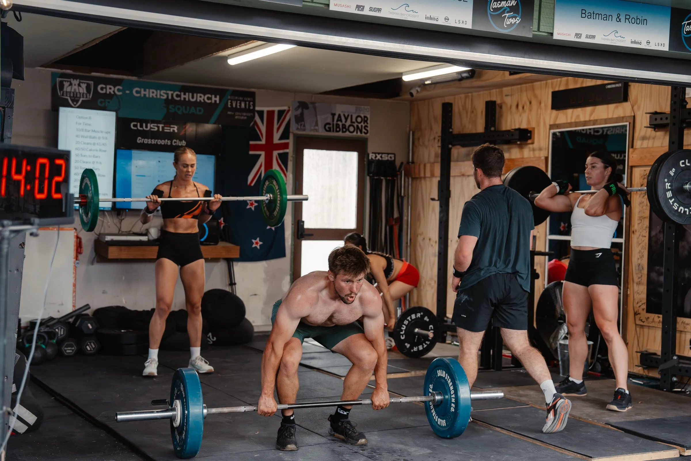 Inside the garage gym — barbells, the NZ flag, and the GRC Christchurch sign.